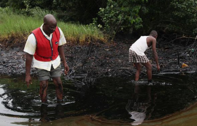 Des hommes marchent dans une nappe de pétrole, dans le delta du Niger, le 20 juin 2010. Des hommes marchent dans une nappe de pétrole, dans le delta du Niger, le 20 juin 2010.