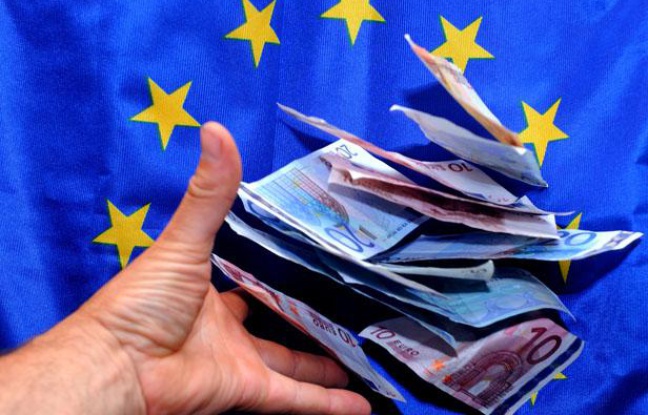 Une personne place des billets en euro devant un drapeau européen. Une personne place des billets en euro devant un drapeau européen.