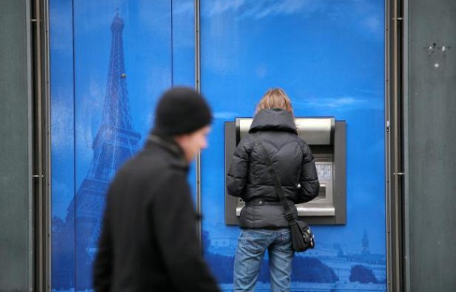 Une femme retire de l'argent dans un distributeur à Paris Une femme retire de l'argent dans un distributeur à Paris