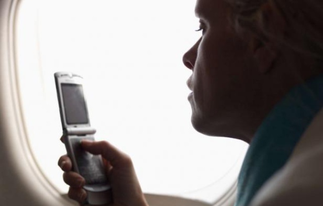 Un passager utilise son téléphone dans un avion. Un passager utilise son téléphone dans un avion.