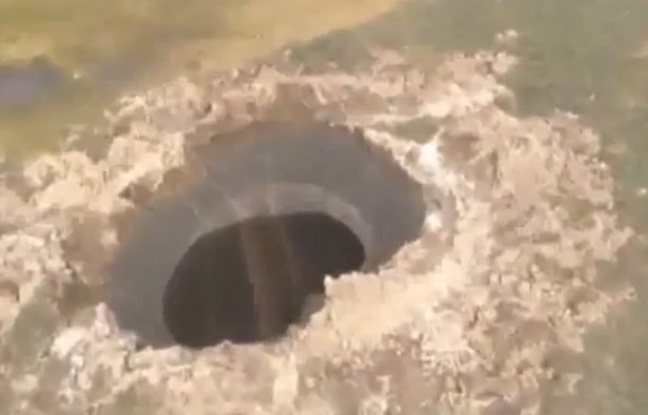 Capture d'écran d'une vidéo d'hélicoptère sur laquelle apparaît un cratère géant en Sibérie. Capture d'écran d'une vidéo d'hélicoptère sur laquelle apparaît un cratère géant en Sibérie.