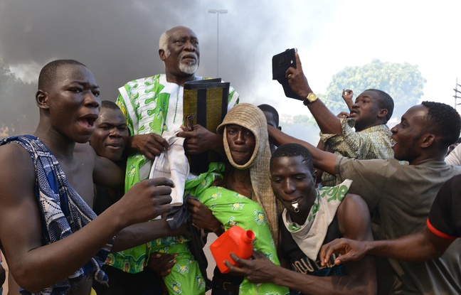 Des manifestants portent un élu de l'opposition devant le Parlement burkinabé à Ouagadougou, le 30 octobre 2014.