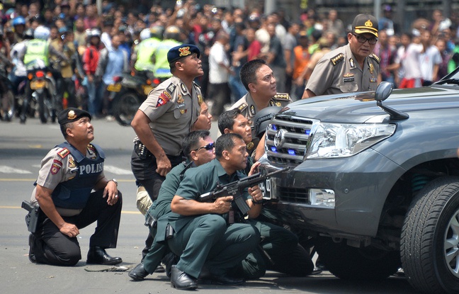Des policiers indonésiens s'abritent derrière un véhicule alors que des explosions ont retenti à Djakarta, le 14 janvier 2016. Des policiers indonésiens s'abritent derrière un véhicule alors que des explosions ont retenti à Djakarta, le 14 janvier 2016.
