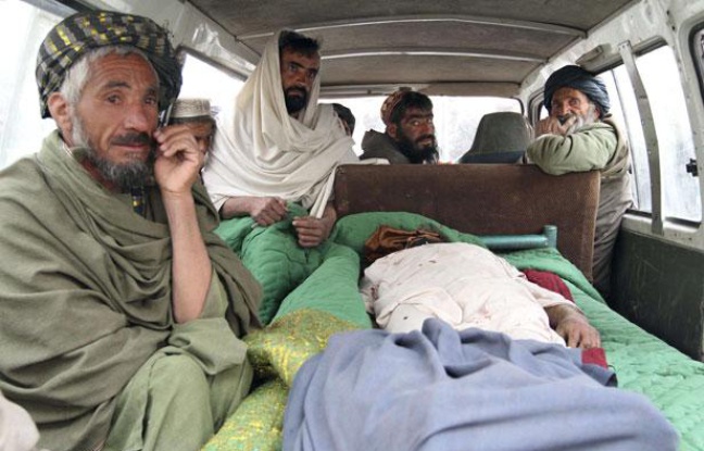 Des civils afghans près du corps d'une des victimes, le 11 mars 2012 Des civils afghans près du corps d'une des victimes, le 11 mars 2012