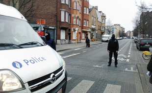Des policiers belges bloquent l'accès où se déroule l'assaut dans le quartier de Molenbeek à Bruxelles, en Belgique le 18 mars 2016.