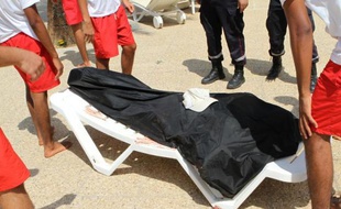 Des maîtres-nageurs tunisiens autour du corps d'un homme tué dans une fusillade dans la station balnéaire de Sousse, le 26 juin 2015