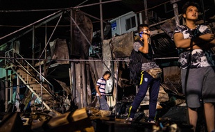 Des migrants devant des containers incendiés au camp de Moria, sur l'île de Lesbos, le 29 septembre 2019.