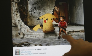 Un journaliste montre le montage d'un artiste syrien alliant guerre en Syrie et Pokémon Go, à Beyrouth, le 22 juillet 2016