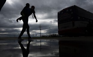 Un homme porte un garçon sur son dos, alors porte un enfant sur le dos alors qu'il se dirige vers un bus pour l'évacuation avant l'arrivée de l'ouragan Laura à Lake Charles, en Louisiane, le 25 août 2020 au milieu de la pandémie de coronavirus.