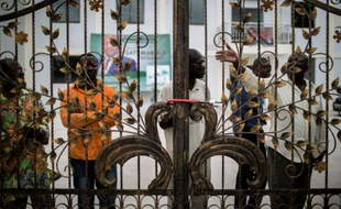 Des militants du parti d'opposition congolais UPADS derrière les grilles cadenassées du siège de leur parti à Brazzaville, le 25 mars 2016