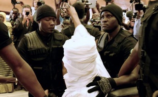 L'ancien président tchadien Hissène Habré (c) est escorté par ses gardiens de prison dans la salle du tribunal à Dakar pour son procès le 20 juillet 2015