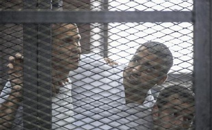 Le journaliste égypto-canadien Mohamed Fadel Fahmy (c) avec ses collègues Peter Greste (g) et Baher Mohamed, lors de son procès au Caire, le 23 juin 2014