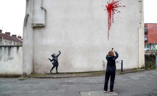 Une passante photographie la nouvelle œuvre de Banksy à Bristol, le 14 février 2020.