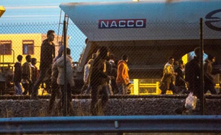 Des migrants marchent sur la voie ferrée en direction du terminal d'Eurotunnel le 11 août 2015 à Fréhun