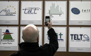 Un homme photographie le nouveau logo (le deuxième en partant de la droite) de la société Tunnel Euralpin Lyon-Turin (TELT), le 8 février 2016 à Lyon