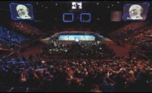 Jeudi soir, deux à trois mille personnes, dont de nombreux compagnons venus de France et 200 de l'étranger (Inde, Bénin, Argentine, Corée, etc.), se sont retrouvés au Palais omnisports de Paris-Bercy, dans la salle principale de plus 10.000 places, trop grande malgré les écrans géants affichant l'image d'Henri Grouès, devenu l'Abbé Pierre.