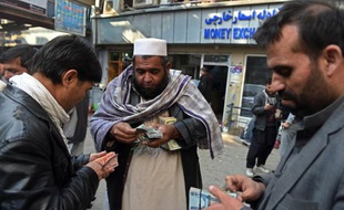 Des changeurs de devises comptent leurs billets dans le marché de Shahzada à Kaboul, le 29 décembre 2014