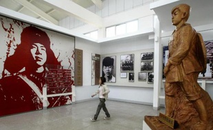 Une femme passe devant un portrait géant du héros-fétiche de la propagande maoïste, Lei Feng le 28 oçctobre 2004 dans son mémorial à Changsha, dans la province chinoise du Hunan