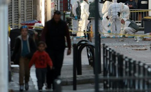 Des enfants et un proche passent devant la police scientifique à Saint-Denis, le 18 novembre 2015