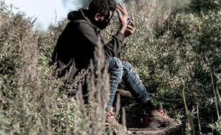 Calais (Pas-de-Calais), le 31 octobre 2016. Un migrant regarde son smartphone dans la «Jungle» de Calais.