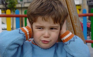 Un petit garçon se bouche les oreilles à cause du bruit (illustration).