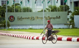 Un garçon en bicyclette passe devant le siège du parti au pouvoir en Birmanie, l'USDP à Naypyitaw, le 13 août 2015