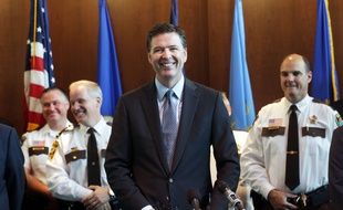 Le directeur du FBI James Comey a annoncé le 17 juin 2014 qu'un suspect dans l'attaque de la mission diplomatique américaine à Benghazi avait été arrêté. a laugh during a news conference Tuesday, June 17, 2014 at the FBI Minneapolis field office in Brooklyn Center, Minn. Comey said the arrest Sunday of a Libyan militant in the deadly attack on Americans in Benghazi is a very good day for law enforcement and added that the FBI's No. 1 priority remains counterterrorism. (AP Photo/Jim Mone)/MP101/46485990026/ /1406172306