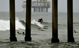 Un surfeur devant une plateforme pétrolière à Huntington Beach, en Californie, le 31 juillet 2015