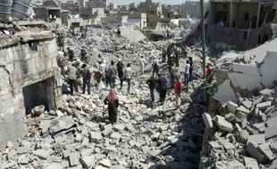 Des habitants d'Alep dans les décombres d'immeubles après des tirs de missiles par le gouvernement syrien, le 21 juillet 2015