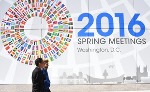 Deux hommes passent devant un panneau annonçant le meeting du monde de la finance à Washington, le 13 avril 2016