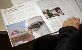 Un journaliste lit le rapport intitulé «Poussés au-delà de nos limites», et publié ce lundi par Médecins Sans Frontières (MSF), à Genève, le 23 mars 2015. AFP PHOTO / FABRICE COFFRINI
