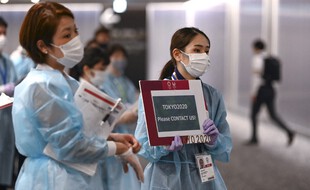 Des volontaires japonais à l'aéroport de Narita, le 18 juillet 2021.