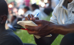 Paris, le 14 juin 2017. Des bénévoles permettent à des migrants d'écouter, écrire, lire et répéter des expressions françaises pour des cours d'alphabétisation improvisés sur la rotonde de la Villette.