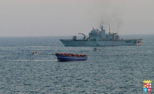 Un bateau de la Marine italienne s'approche d'une embarcation en difficulté remplie de migrants, le 2 avril 2014 en Méditerranée