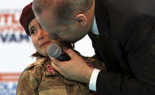 Le président turc Recep Tayyip Erdogan, embrassant une petite fille qui a revêtu la tenue militaire turque, lors d'un congrès de l'AKP le 24 février 2018.