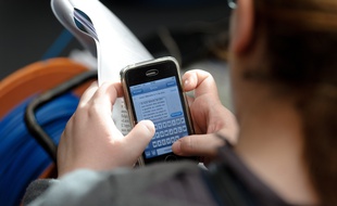 Paris le 09 janvier 2012. Redaction d'un message SMS sur un smart phone Iphone.