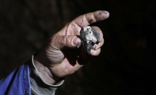 Un mineur montre un fragment de pierre contenant de l'uranium.