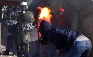 Un manifestant jette un cocktail molotov sur des policiers à Athènes, le 19 octobre 2011.