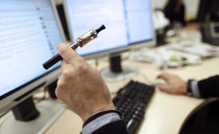 Un homme fume sa cigarette électronique au travail