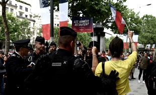 Des gendarmes entourent une manifestante sur les Champs-Elysées, le 14 juillet.