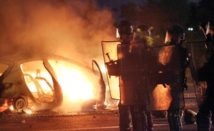 Des forces de l'ordre près d'une voiture brûlée par des manifestants, au Port (La Réunion), le 19 février 2013.