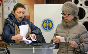 Des femmes glissent leur bulletin dans l'urne dans un bureau de vote de Chisinau le 30 novembre 2014