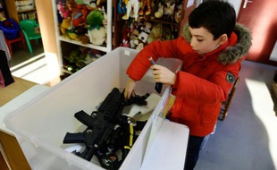 Edouard, 9 ans, dépose des jouets factices dans une caisse en plastique, à Ris-Orangie (Essonne), le 9 décembre 2015