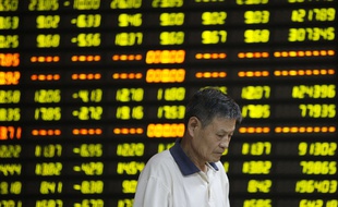 Un homme passe devant un tableau des cours financiers à Huaibei, dans la province chinoise d'Anhui, le 27 juillet 2015.