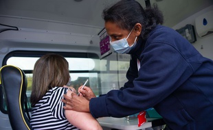 Illustration d'une jeune femme se faisant vacciner en Grande-Bretagne.