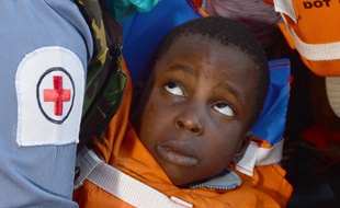 Une assistante médicale de la Royal Navy prend en charge un enfant sauvé au large des côtes libyennes le 13 mai 2015.