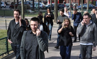 Groupe de personnes téléphonant dans la rue.
