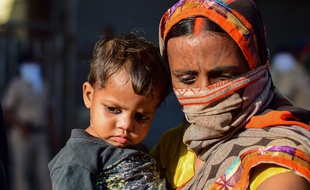 Une femme et son enfant attendent un bus du gouvernement qui les ramènera dans leur région, à Bombay le 19 mai 2020.