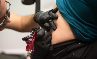 Un tatoueur à l'oeuvre. Image d'illustration.