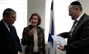 Beate Klarsfeld (C) reçoit des mains du ministre de l'Intérieur israélien Arye Deri (D) et du directeur du mémorial de Yad Vashem, Avraham Shalev, sa carte d'identité et son passeport israéliens, lors d'une cérémonie au minstère de l'Intérieur à Jérusalem, le 15 février 2016